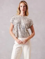 Blusa de manga corta cubierta de lentejuelas en tono champagne, con cuello redondo a la base y forro interno a tono.