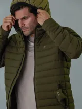 Campera acolchada verde militar con capucha, cierre frontal con cremallera y bolsillos laterales con cremallera.