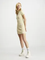 Sweater de punto canalé color crema, ajustado al cuerpo, con cuello mock y mangas cortas. Presenta costuras visibles que definen la silueta y un pequeño bolsillo decorativo en el pecho. Incluye una etiqueta con el logo 'CK' en el bajo.