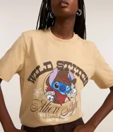 Remera de algodón color beige, modelo t-shirt, con cuello redondo, manga corta y estampa frontal de Stitch con temática de cowboy y lettering "Wild Stitch".