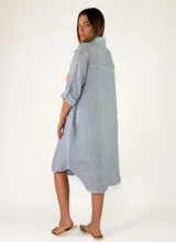Camisola midi confeccionada en lino color gris, con diseño amplio y fluido, cuello camisero, cierre frontal con botones y mangas largas con presilla para arremangar.