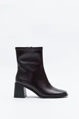 Bota de caña baja color negro, confeccionada en poliuretano con acabado brillante, puntera cuadrada y taco medio geométrico.