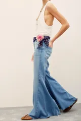 Pantalón jean de corte flare y tiro medio, color celeste con efecto lavado, de diseño amplio en la parte inferior y dobladillo deshilachado.