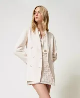 Blazer cruzado de lana color crudo, con solapas, cierre con botones a tono, manga larga con aberturas y bolsillos con solapa.