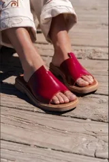 Sandalias rojas con base marrón y tira ancha que separa el dedo gordo del resto.