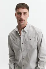 Camisa manga larga color verde oliva, corte slim fit, con cartera abotonada, dos bolsillos frontales con botón y confeccionada en 100% algodón.