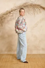 Bomber estampada con diseño abstracto multicolor, cuello mao y cierre frontal con botones dorados.