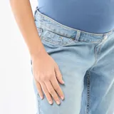 Jeans de maternidad con corte mom, de tiro alto y color azul claro. Presenta un diseño clásico con costuras visibles y terminación de botamanga deshilachada.