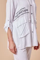 Sobrecamisa blanca de viscosa con capucha, cordón ajustable, bolsillos con apliques y botones metálicos.