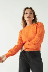 Sweater tejido color naranja, con cuello redondo y diseño de ochos en relieve. Corte a la cintura y mangas largas.