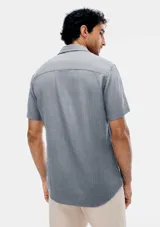 Camisa de manga corta celeste con estampado de micromercado, cuello camisero, cierre frontal con botones y un bolsillo ojal en el pecho.