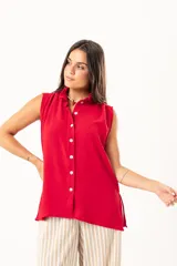 Camisa roja sin mangas con cuello mao adornado con un volado y cierre frontal con botones.