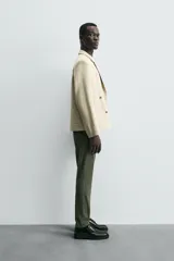 Pantalón chino de corte ajustado, color beige, con bolsillos laterales y bolsillos traseros de vivo. Cuenta con cierre frontal de cremallera y botón.