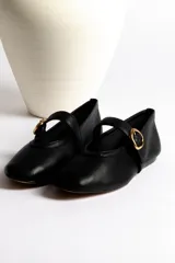 Ballerinas negras de cuero con tira sobre el empeine y hebilla dorada.