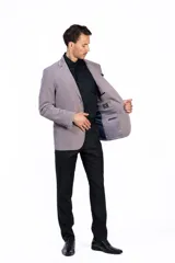 Blazer de pana color gris topo, con solapas de muesca, cierre de dos botones y bolsillo de parche en el pecho con pañuelo decorativo.