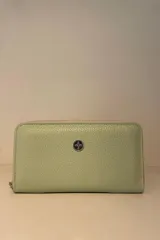 Billetera con cierre perimetral, color verde pastel, con textura granulada y logo metálico en el frente.