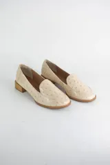Mocasin de cuero con textura tipo avestruz en color beige, con punta redonda y taco bajo simil madera.