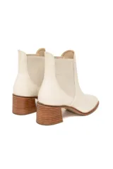 Botines tipo Chelsea de cuero color off-white, con paneles laterales elásticos a tono, punta ligeramente cuadrada y tacón de bloque de madera.