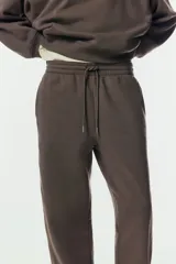 Pantalón deportivo de tiro alto confeccionado en felpa de mezcla de algodón con interior cepillado. Presenta cintura elástica con cordón de ajuste, bolsillos laterales al bies y puños elásticos en los bajos.
