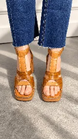 Sandalias de taco alto ancho con plataforma, color tostado, con tiras delanteras entrelazadas en cuero grabado tipo cocodrilo y capellada lisa, tiras laterales y correa al tobillo con hebilla metálica ajustable.