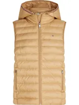 Chaleco acolchado color beige con capucha desmontable, cierre frontal con cremallera, dos bolsillos laterales con cremallera y logo de Tommy Hilfiger bordado en el pecho. Confeccionado en poliéster reciclado con acabado repelente al agua.