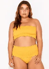 Conjunto de bikini amarillo con corpiño bandeau con volados y bombacha de tiro alto con volados.