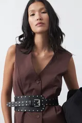 Chaleco sastrero de color marrón, con silueta recta, escote en V y cierre frontal con botones. Presenta una estructura definida y tejido con caída firme.