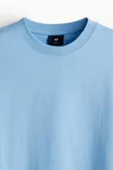 Remera de algodón celeste de corte relajado, con cuello redondo ribeteado y mangas cortas con hombros caídos.