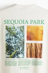 Remera de algodón color crema con cuello redondo y estampa frontal en color verde con el texto Sequoia Park y pequeños iconos gráficos.