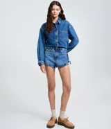 Camisa oversized de jean azul, con cuello padre, mangas largas con puños abotonados y cierre frontal con botones. Incluye un bolsillo aplicado en el pecho y bajo redondeado.