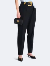 Bolso mini Balmain modelo B-Buzz, color negro, con asa superior rígida y correa de hombro extraíble. Presenta solapa con cierre de broche a presión y aplique metálico dorado con el logo de la marca.