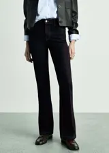 Pantalón de jean tiro medio con diseño de corte campana (flare), cinco bolsillos y cierre frontal con cremallera y botón.