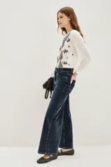 Pantalón de jean estilo corderoy negro, de corte wide leg y tiro alto, con bolsillos delanteros parcheados.