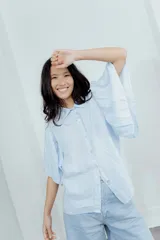 Camisa de lino color celeste, con cuello clásico, cierre frontal con botones y mangas cortas amplias con diseño de volados.