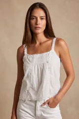 Blusa de algodón blanca sin mangas, con escote cuadrado, detalles de encaje y bordados delicados en los laterales y el dobladillo.