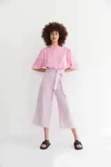 Pantalón culotte de lino color lila, tiro alto, con detalle de lazo ancho en la cintura y corte ancho que termina a media pierna.