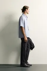 Jeans regular fit de mezclilla negra con efecto lavado, corte recto y tiro medio. Cuenta con diseño de cinco bolsillos y cierre frontal con cremallera y botón.