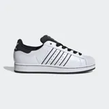 Championes Adidas Superstar blancos con detalles en negro, incluyendo las tres tiras laterales y el contrafuerte. Presentan la puntera de goma característica y cordones negros.