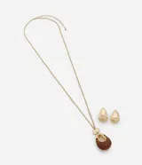 Conjunto de bisutería compuesto por un collar largo con cadena dorada y dije en forma de gota con detalle de resina, y un par de aros tipo argolla gruesa con baño en tono dorado.