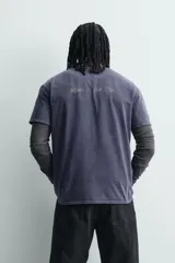 Camiseta de corte relajado con cuello redondo y manga corta. Presenta un acabado con efecto lavado que le otorga una apariencia única y desgastada. Incluye estampados a contraste en la parte frontal.