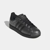 Championes Adidas Superstar II, modelo clásico de caña baja en color plateado metalizado con detalles en negro, incluyendo las tres tiras icónicas, los cordones, la suela y el refuerzo del talón. Cuentan con la tradicional puntera de caucho con relieve y exterior de cuero.