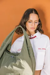 Bolso deportivo tipo duffel bag de nylon color verde oliva, con asas de mano y correa ajustable para llevar al hombro.