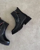 Botín de cuero color marrón con suela track negra y cierre lateral.