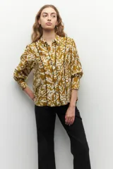 Camisa color ocre con estampado floral blanco, de manga larga, con botones de nácar y bordados a contratono.