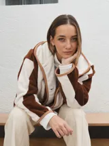 Campera con capucha, de tela tipo peluche a rayas verticales color marrón y blanco, con ribete color beige.