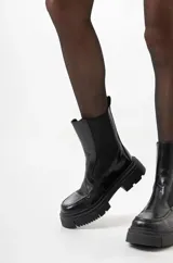 Botines negros estilo Chelsea de caña media, con elástico lateral y suela chunky dentada.