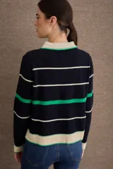 Buzo de punto con cuello polo y cierre frontal de tres botones. Diseño a rayas horizontales en tonos crema, bordó y mostaza, con detalle de bordado en el pecho.