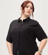 Vestido chemise midi color negro confeccionado en viscosa, de corte recto y holgado. Cuenta con cuello camisero, mangas cortas y cierre frontal con botones al tono.
