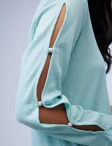 Blusa tejida color celeste con lurex, de manga larga con aberturas y apliques de brillo. Ruedo anudado.