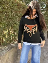 Sweater de punto fino color negro con diseño frontal de búfalo en cuero y bordados artesanales. Presenta cuello redondo con detalle en color tostado y mangas largas.